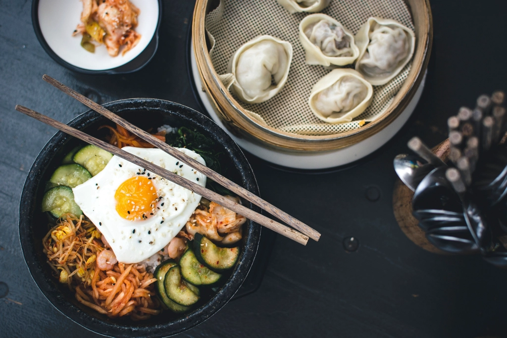 Koreanische Reis-Bowl mit Spiegelei, Gemüse und Dumplings